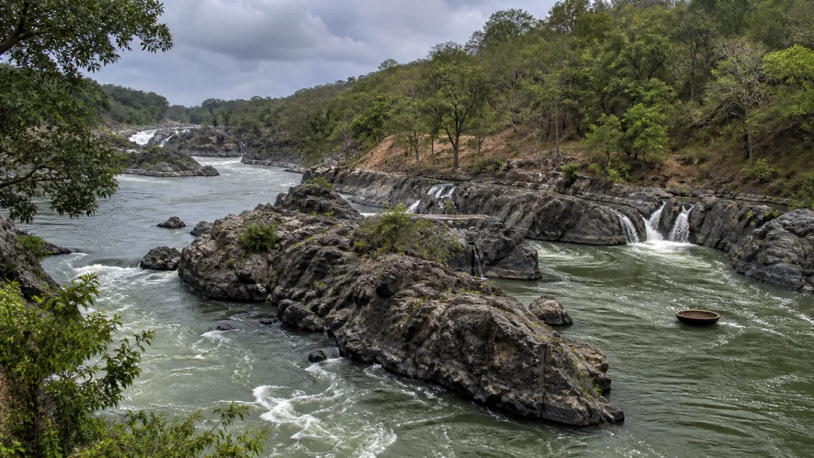 Editorial interpretation of the Cauvery flowing through Hogenakkal's rocky channels with a distant coracle on calm water