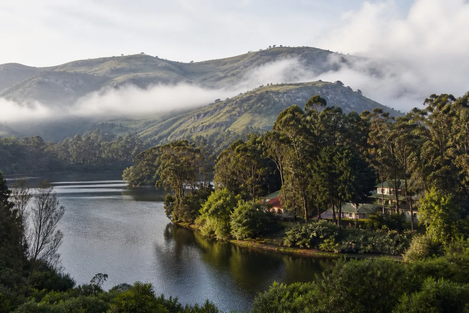 Editorial view of Kodaikanal lake, wooded slopes and misty Palani Hills