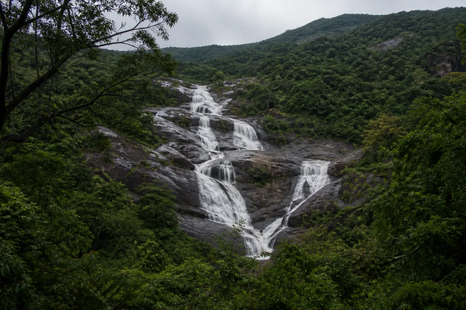 Seasonal waterfall descending over dark rock in a forested Western Ghats landscape